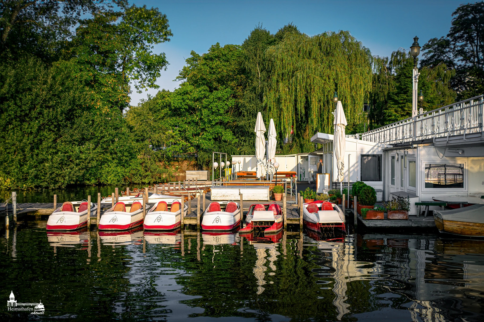 Bootsverleih am Anleger Rabenstraße an der Außenalster in Hamburg mit Tretbooten im Abendlicht.