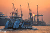 Hafenfähre bei Sonnenuntergang im Hamburger Hafen mit Werftkränen im Hintergrund