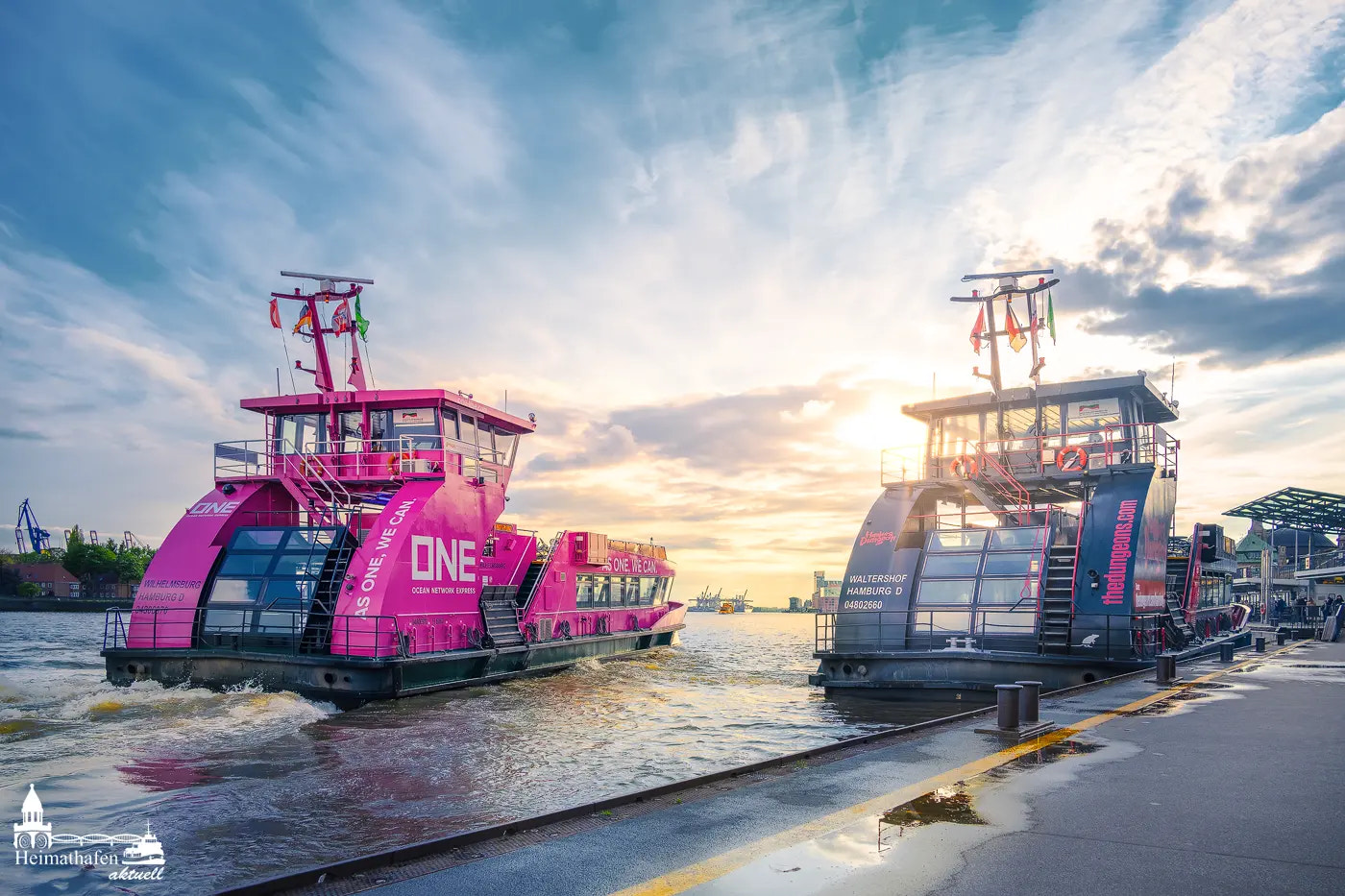 Rosa HVV-Fähre „ONE“ und schwarze HVV-Fähre an den Landungsbrücken in Hamburg bei Sonnenuntergang