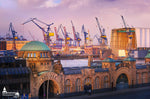 Die Hamburger Landungsbrücken bei Sonnenaufgang mit Blick auf die Werften und Hafenkräne.