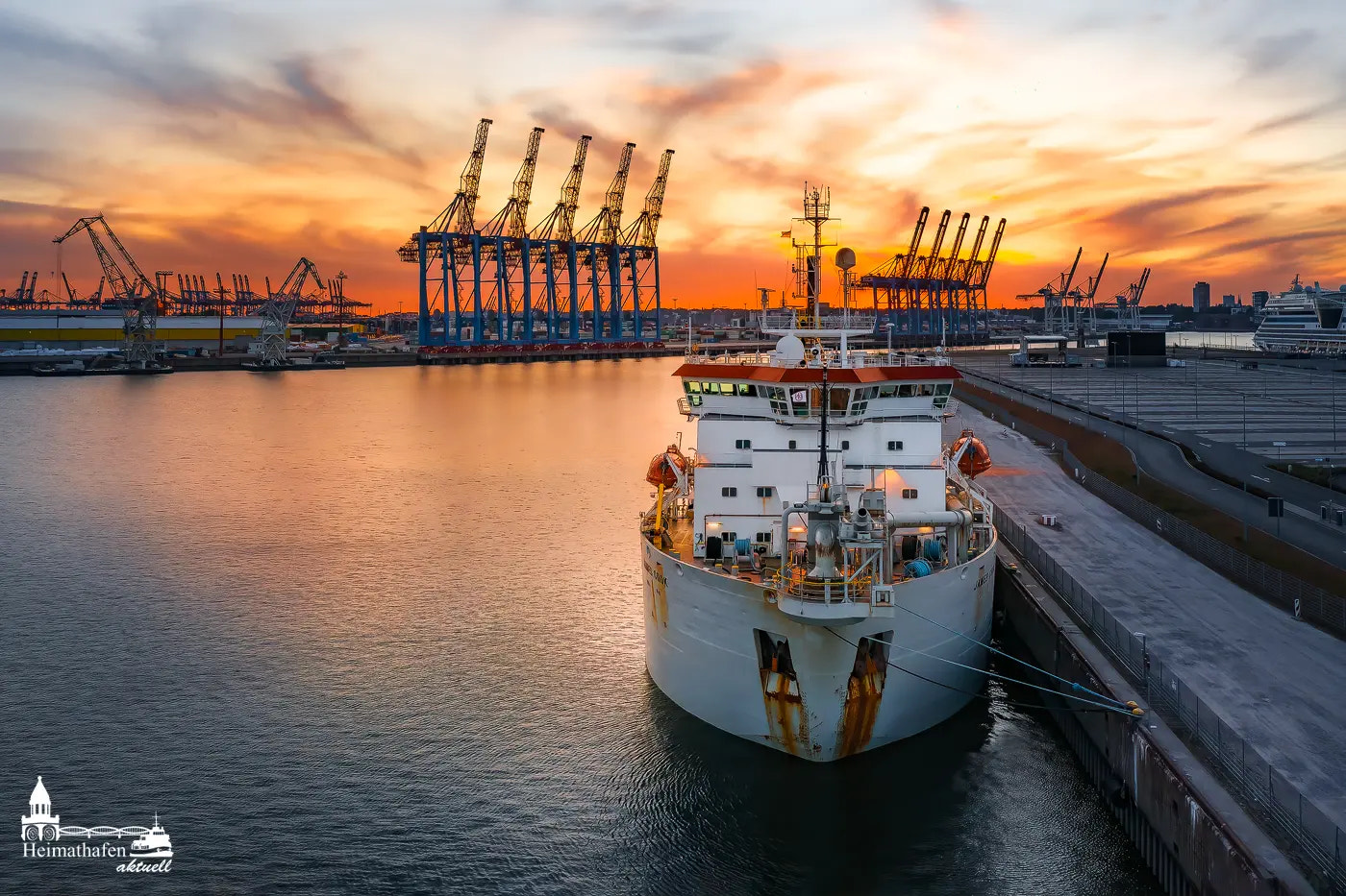 Schlickbagger JAMES COOK im Hamburger Hafen bei Sonnenuntergang mit Containerbrücken im Hintergrund
