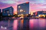 Sonnenuntergang über dem Spiegelgebäude in Hamburg mit violettem Himmel und Lichtspiegelung im Wasser.