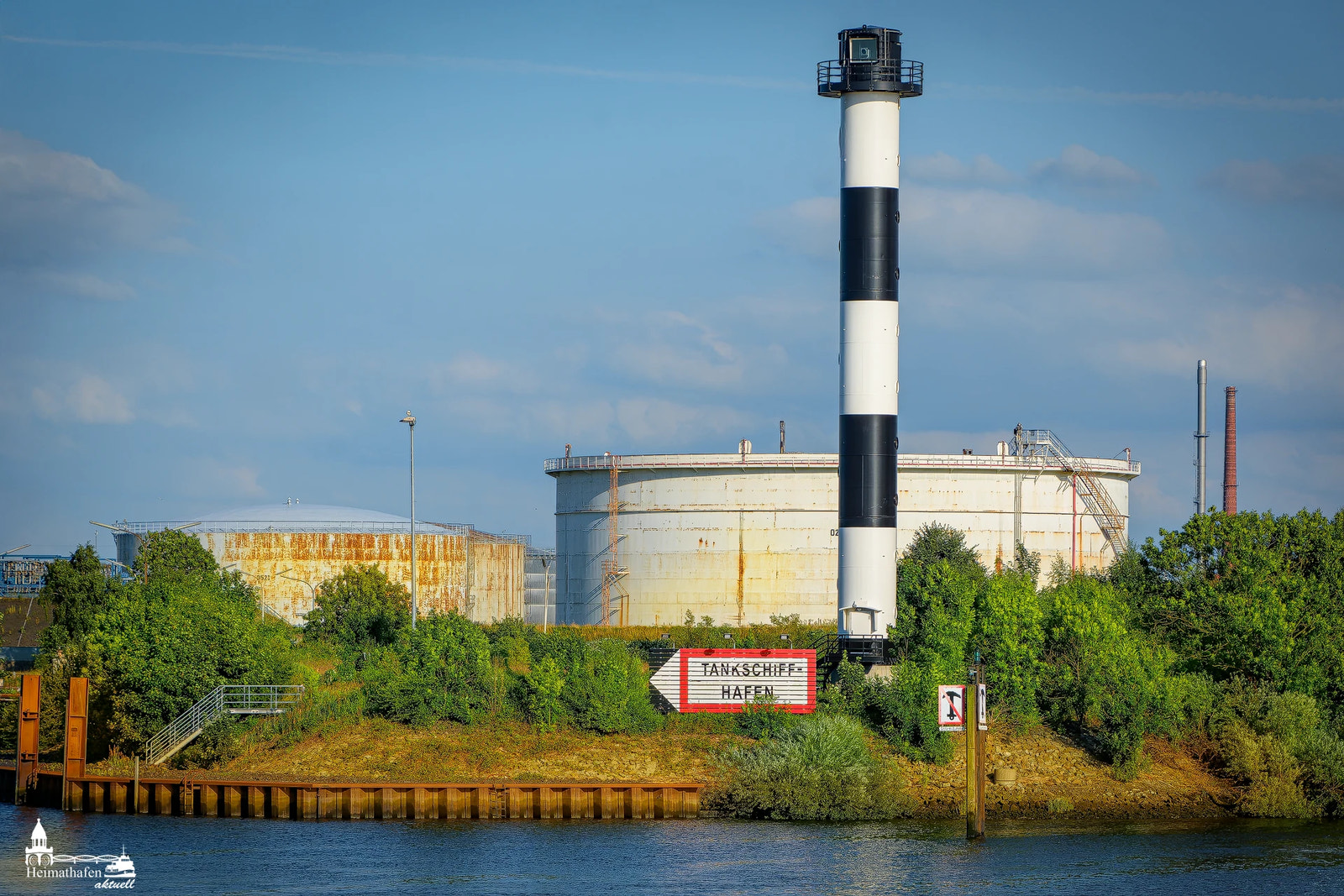 Leuchtturm und Öltanks am Tankschiffhafen Hamburg-Wilhelmsburg bei Sonnenschein
