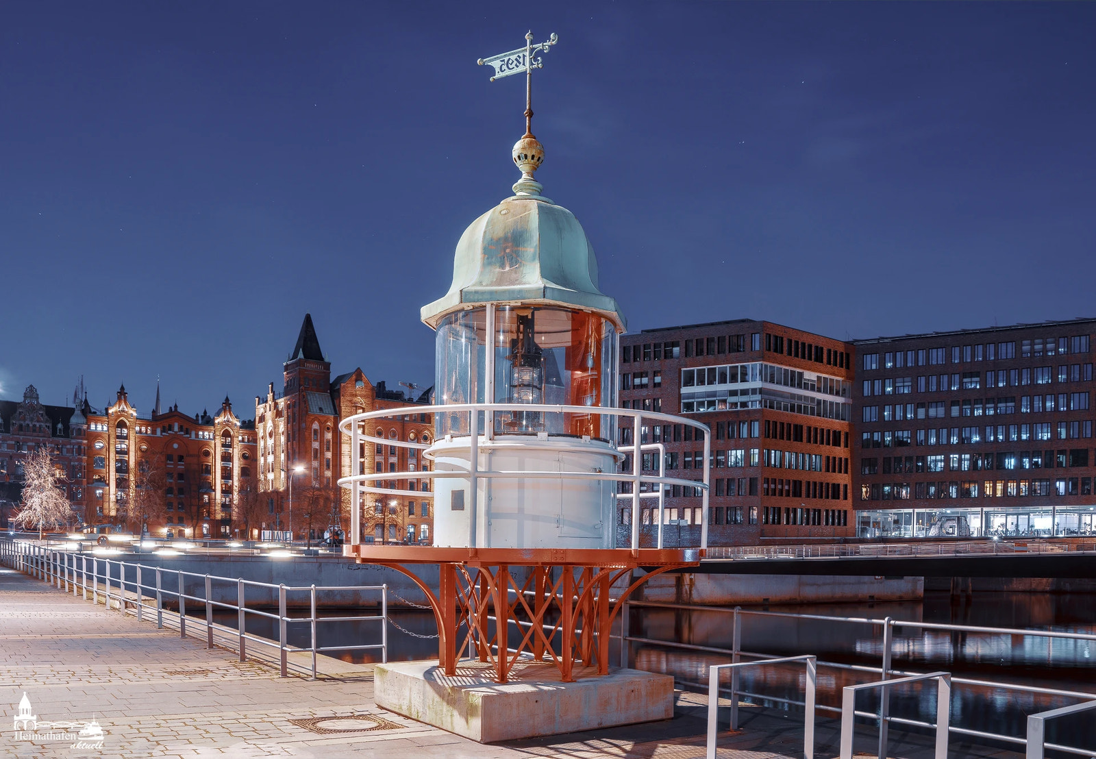 Historisches Leuchtfeuer in der Hamburger HafenCity bei Nacht, mit beleuchteter Speicherstadt im Hintergrund